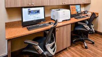A workspace with two computers, a printer, and office chairs.