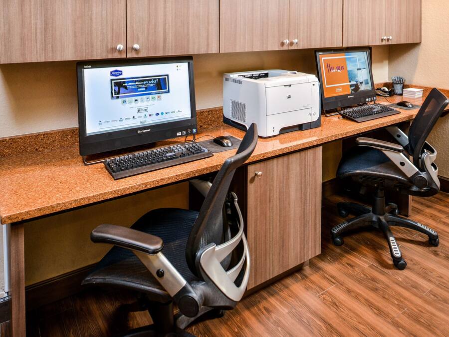 A workspace with two computers, a printer, and office chairs.