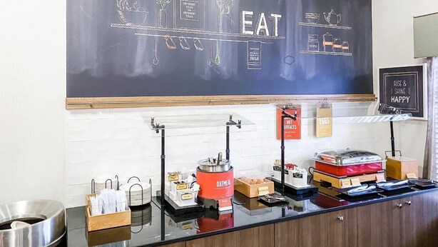 Ein Frühstücksbuffet mit einer Schiefertafel, die Speisen und Besteck zeigt.