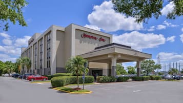 Ein Hampton Inn Hotel mit blauem Himmel und Autos auf dem Parkplatz.