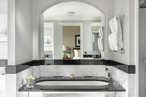 A modern bathroom with a large mirror, a bathtub, and a sink.