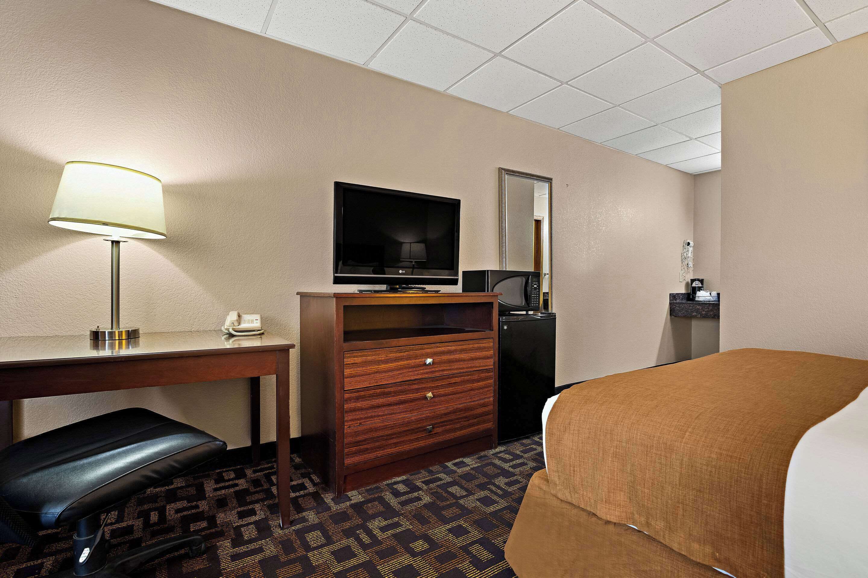Une chambre d’hôtel équipée d’un bureau, d’une chaise, d’une télévision, d’une commode et d’un lit.
