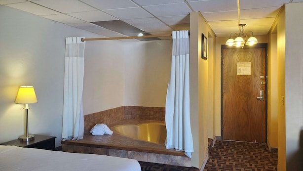 Une chambre d’hôtel avec un grand lit, une baignoire et un banc en bois.