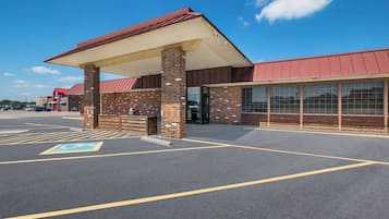 A building with a brick facade, a covered entrance, and a parking lot with marked handicapped spaces.