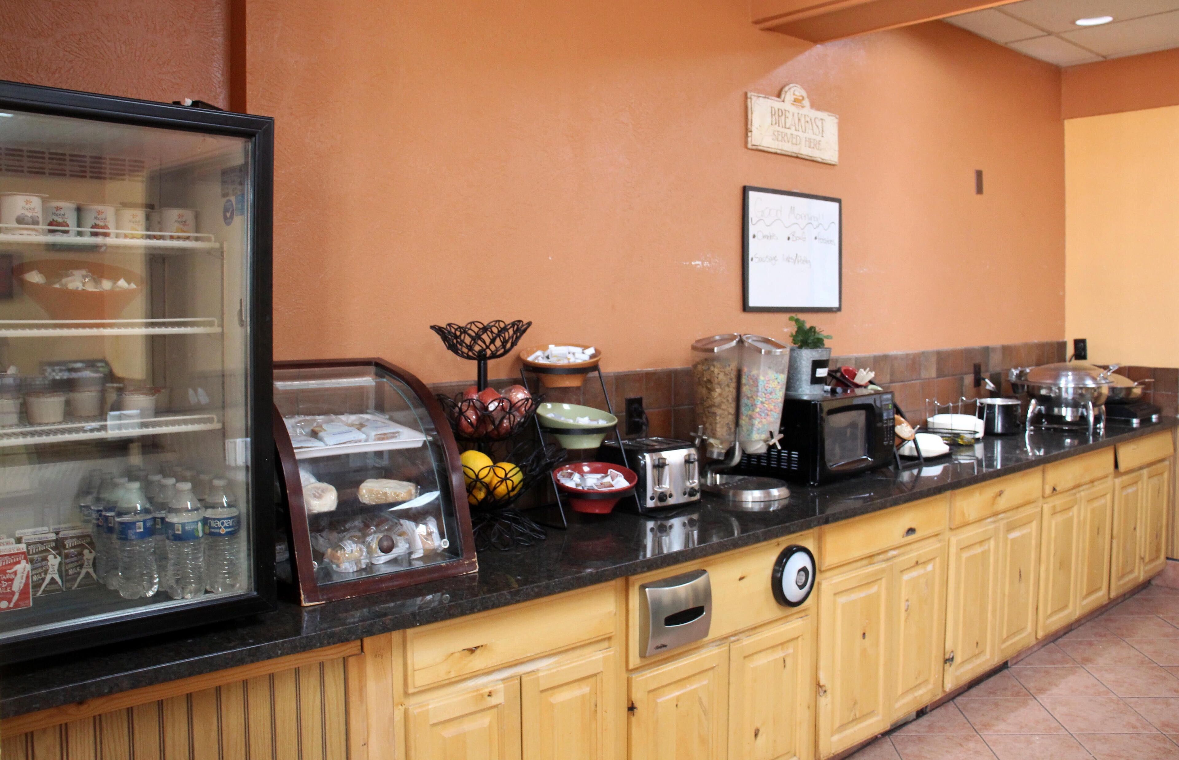 Una barra de desayuno con diversos alimentos y un refrigerador con bebidas.