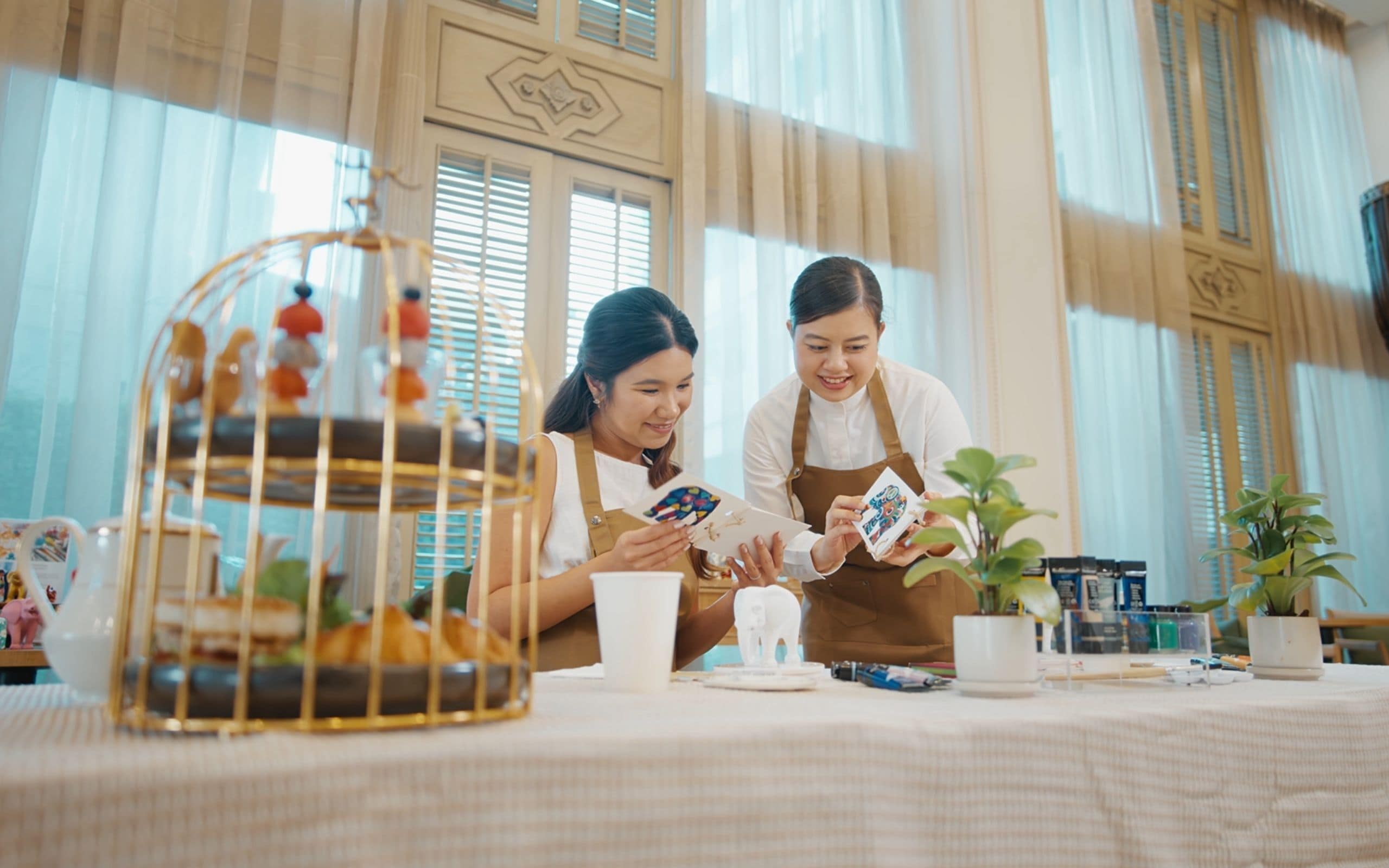 Dos personas sentadas a una mesa con un pastel, una taza y una planta.