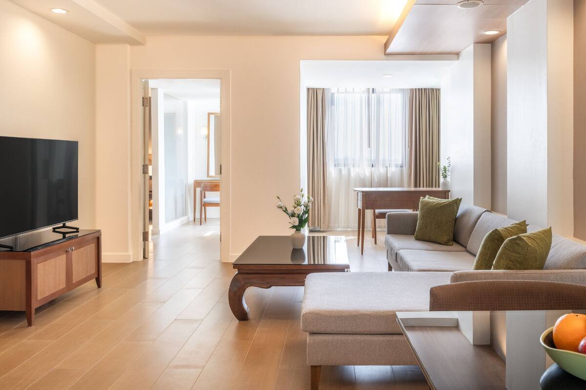 Ein modernes Wohnzimmer mit Flachbildfernseher, einer Couch, einem Couchtisch und einem Essbereich mit Tisch und Stühlen.