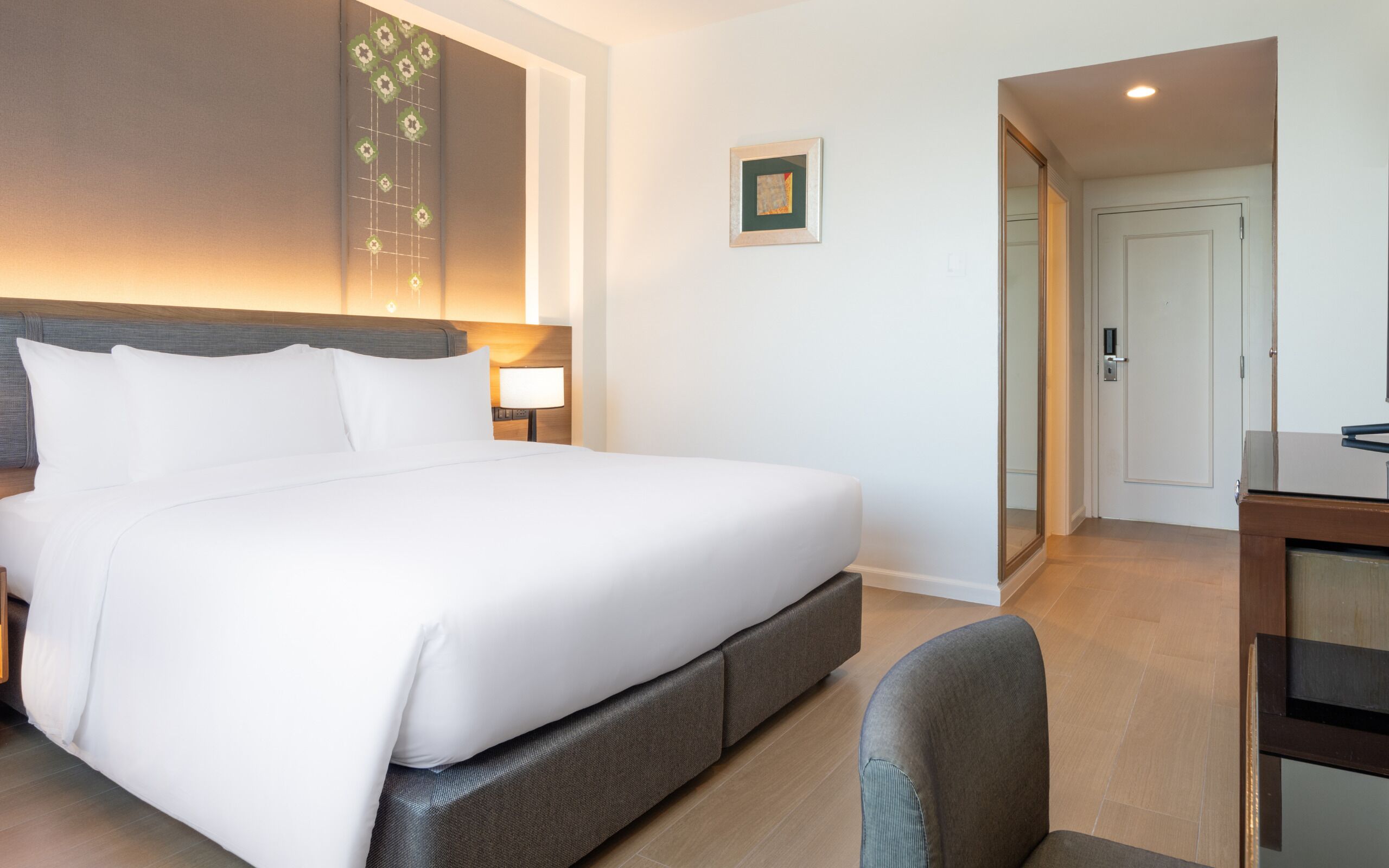 Ein Hotelzimmer mit einem großen Bett, einem Schreibtisch und einem Spiegel.