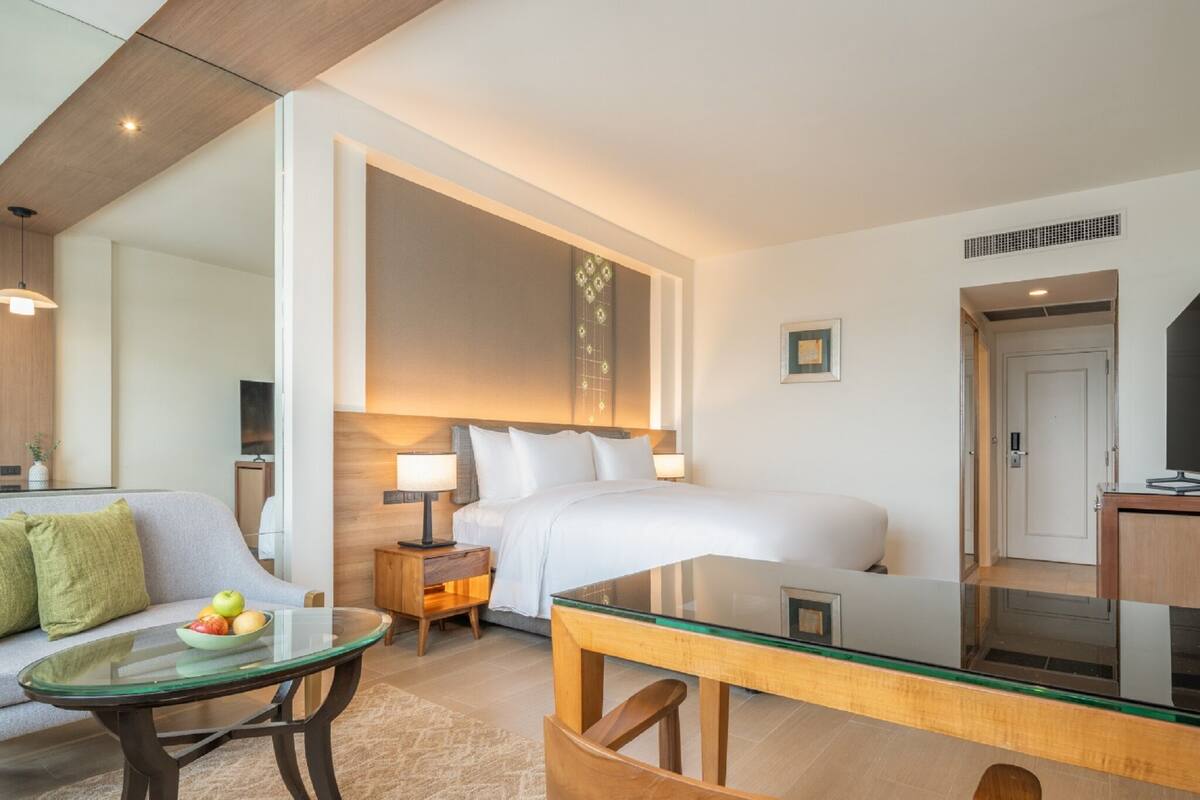 Ein modernes Hotelzimmer mit einem großen Bett, einem Glastisch, einer Couch und einem Schreibtisch.