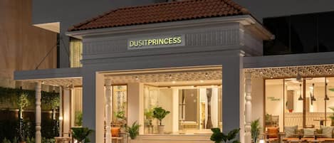Un hotel llamado "DUSITPRINCESS" con entrada cubierta, zona de estar al aire libre y plantas en macetas.