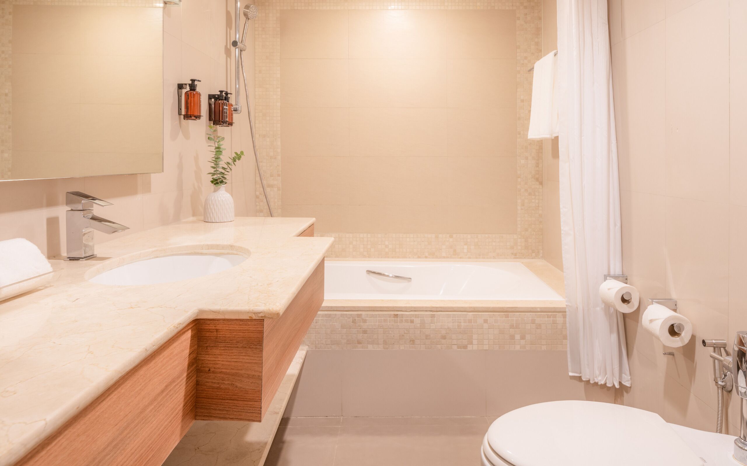 A modern bathroom with two sinks, a bathtub, and a toilet.