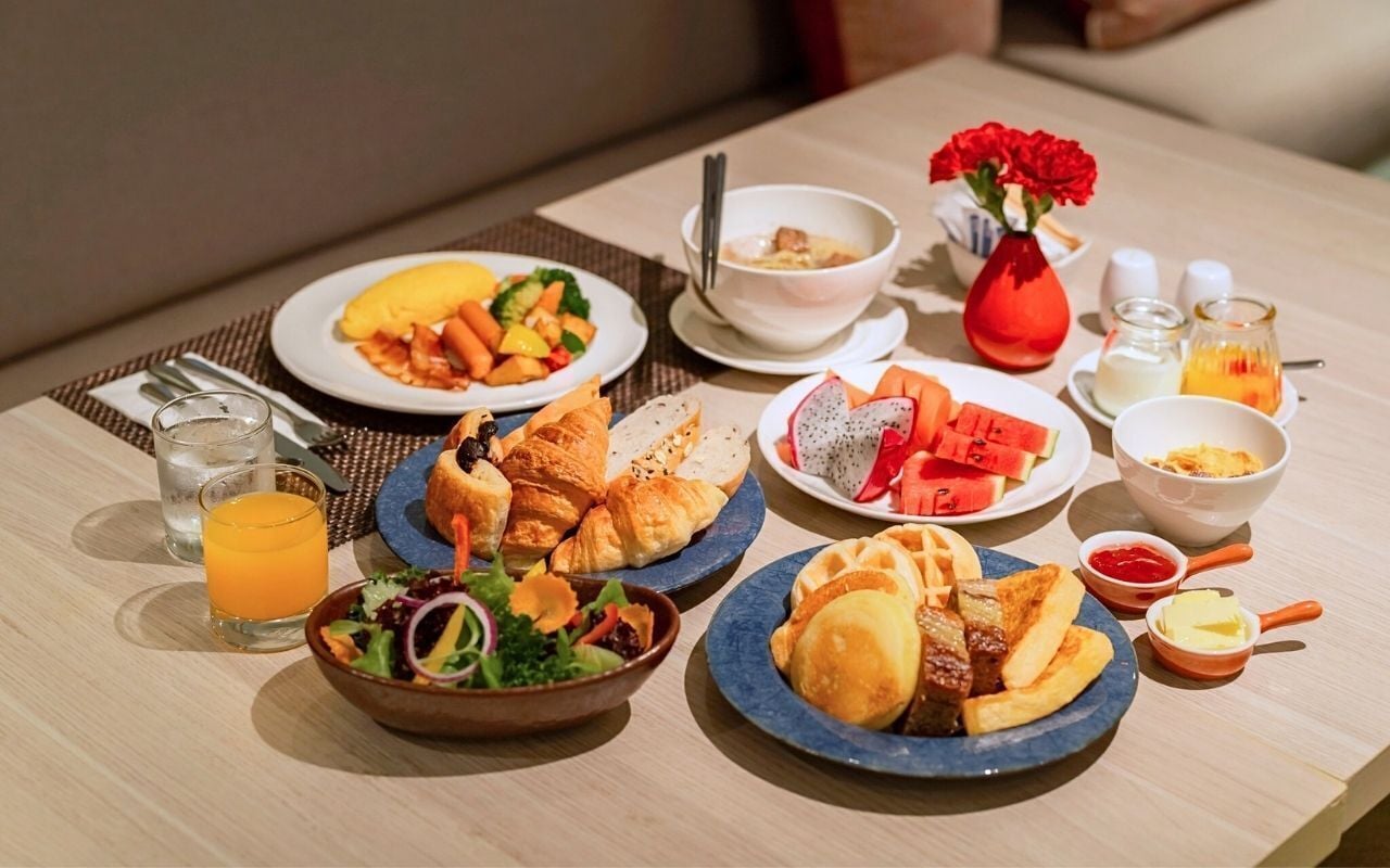 A breakfast buffet with various dishes, including croissants, fruit, and a salad.