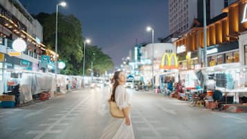 A nighttime street scene with a pedestrian crossing and various commercial establishments, including a McDonald's.