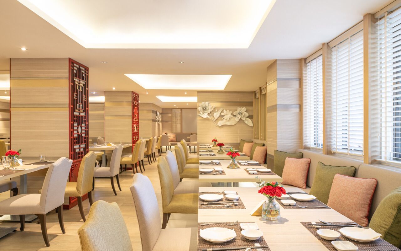 A modern dining area with long tables, chairs, and decorative elements like flowers and wall art.