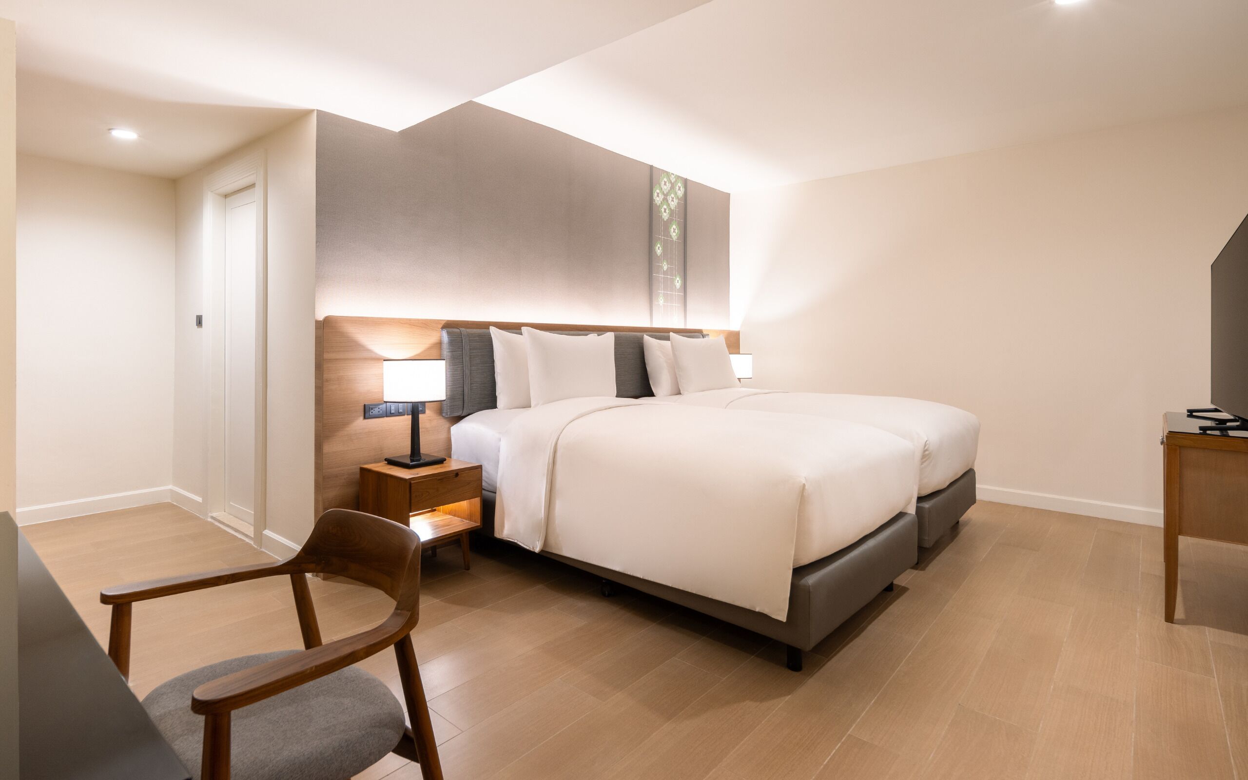 Una habitación de hotel moderna con una cama grande, mesitas de noche, una silla y un escritorio.