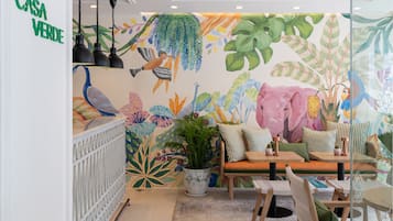 A cozy indoor space with a vibrant mural, a seating area with a table and chairs, and a potted plant.