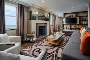 A modern living room with a fireplace, a large sofa, a coffee table, and a bookshelf.
