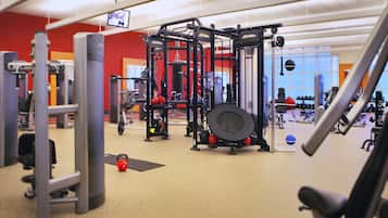 A gym with various exercise equipment, including a squat rack, benches, and weights.