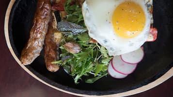 Un plato con un huevo frito, salchicha y una ensalada de rábanos.