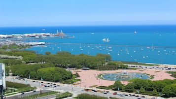 Un puerto deportivo con barcos y yates, una gran fuente y una calle concurrida con coches y autobuses.