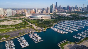 A marina with numerous boats docked, surrounded by a cityscape with high-rise buildings and a stadium. - Hilton Chicago (Chicago)