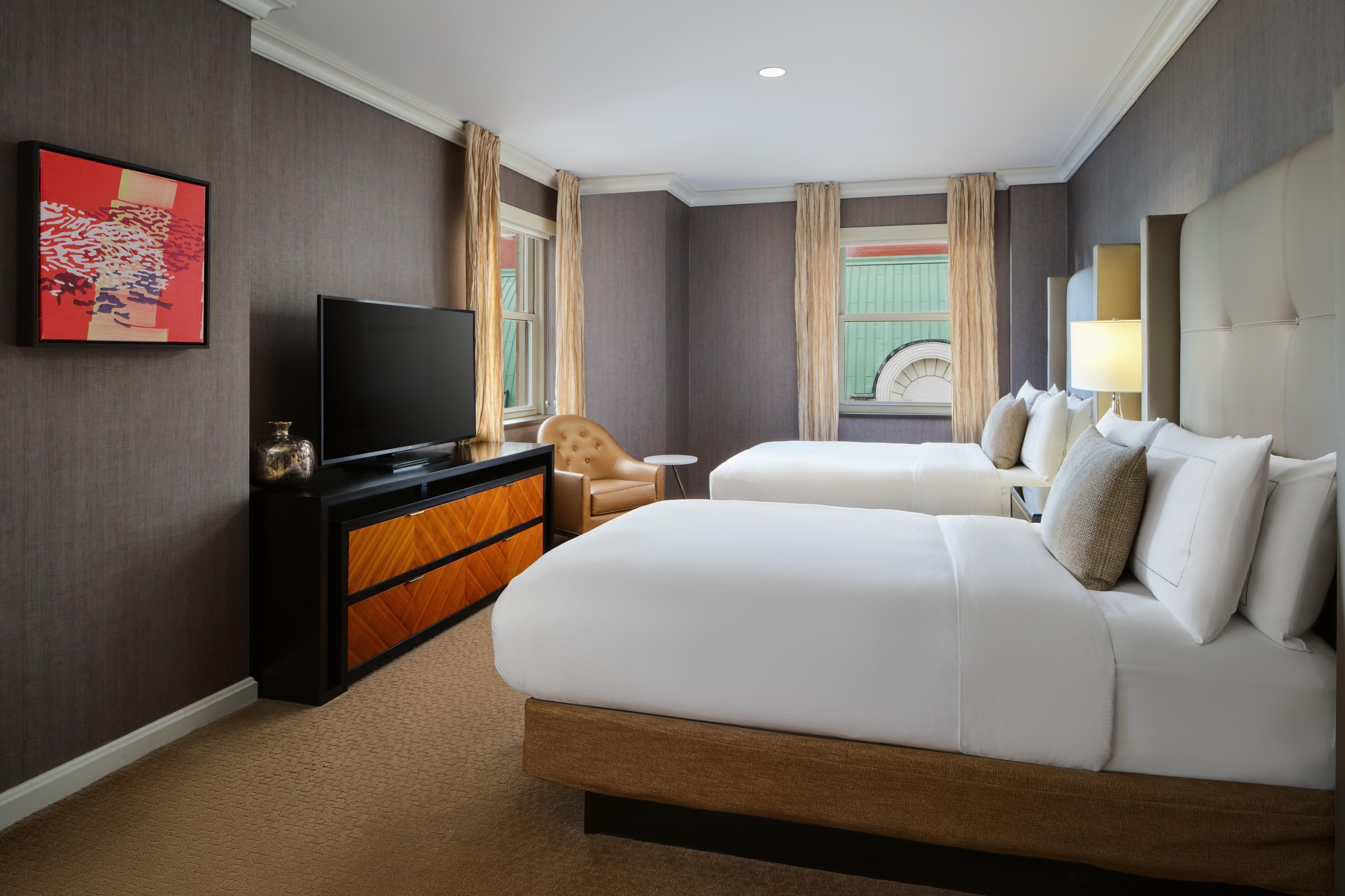 A hotel room with a large bed, a television, a small table, and a chair.