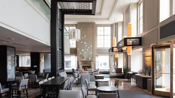 A spacious hotel lobby with a high ceiling, modern furniture, and large windows allowing natural light.