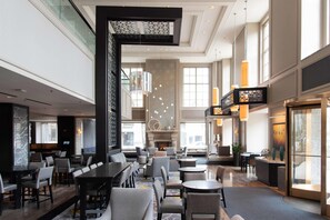 A spacious hotel lobby with a high ceiling, modern furniture, and large windows allowing natural light. - Hilton Chicago (Chicago)