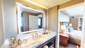 A hotel bathroom with a large mirror, a marble sink, and a wooden vanity.
