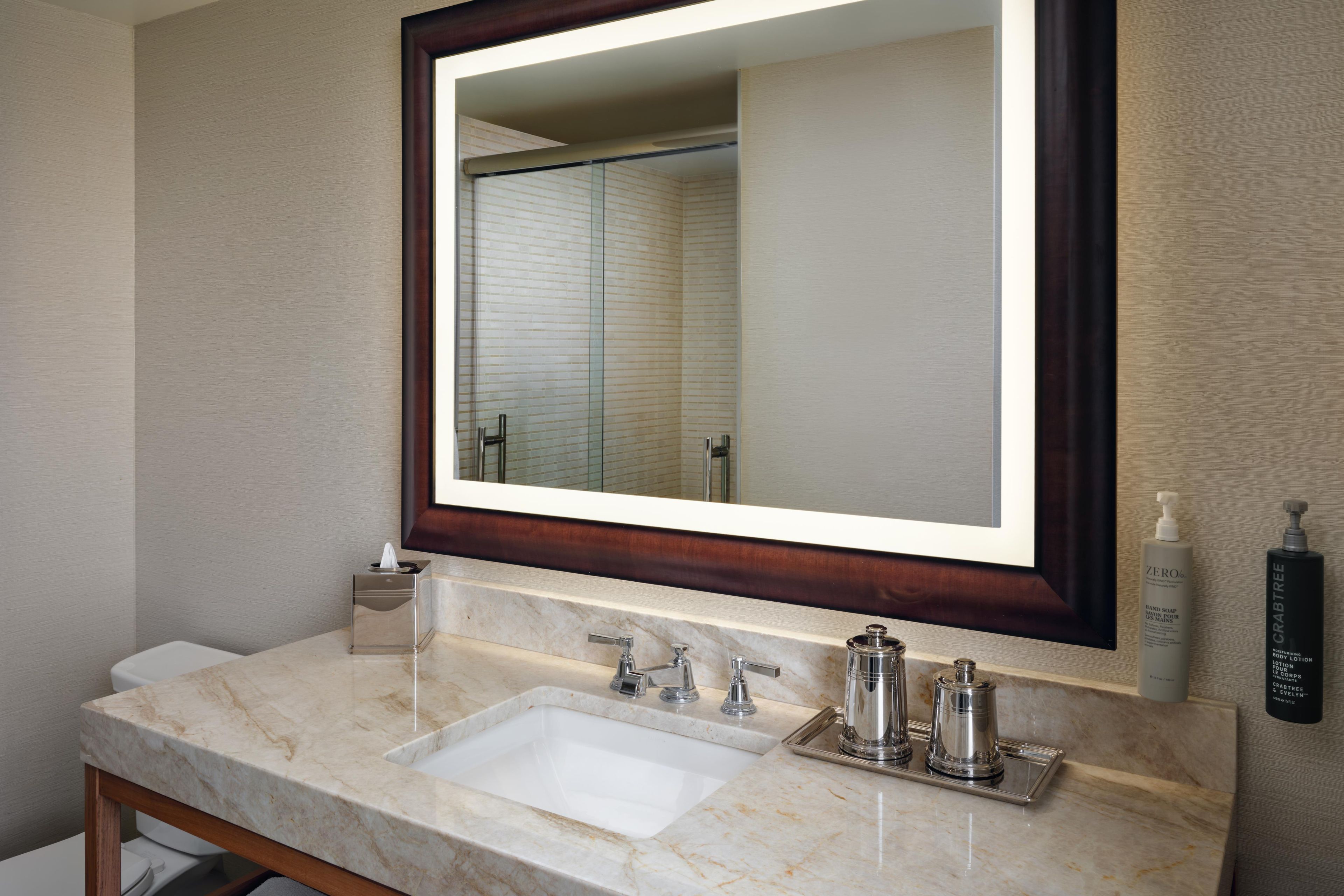 A bathroom with a marble sink, a large mirror, and toiletries.