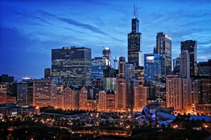A city skyline at dusk with illuminated buildings and a prominent skyscraper. - Hilton Chicago (Chicago)