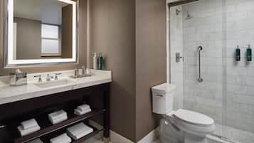 A modern bathroom with a large mirror, two sinks, a toilet, and a glass-enclosed shower.