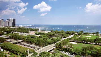 A park with a fountain, a bridge, and a view of the sea with boats.