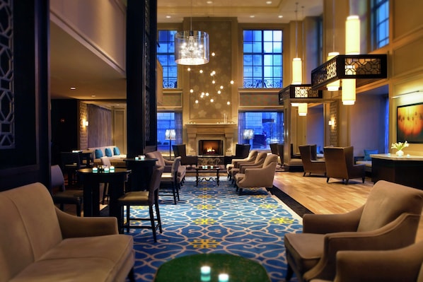 A spacious lobby with a patterned carpet, comfortable seating, a fireplace, and large windows. - Hilton Chicago (Chicago)