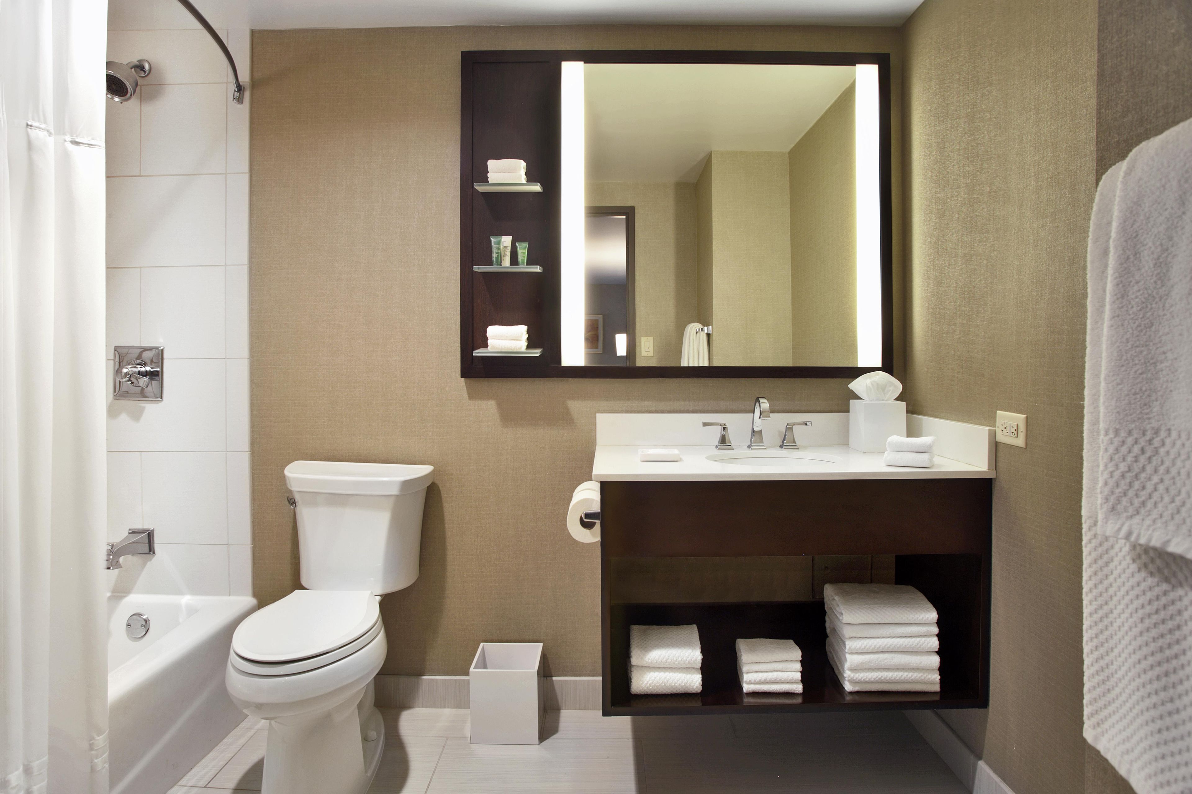 Un baño moderno con inodoro, lavamanos y espejo.