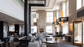 A spacious hotel lobby with a long reception desk, multiple seating areas, and a large fireplace. - Hilton Chicago (Chicago)