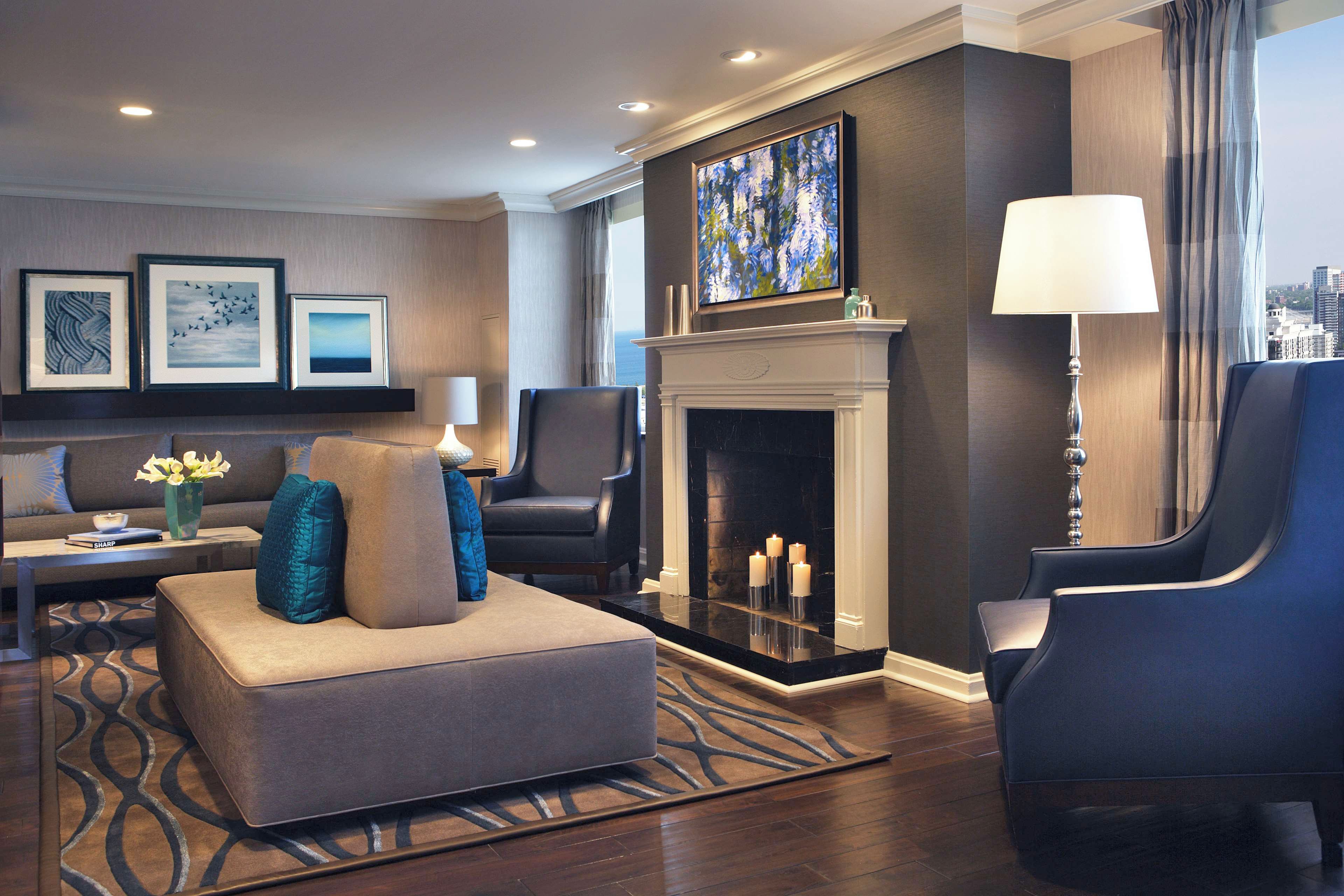 A modern living room with a fireplace, seating area, and artwork on the walls.