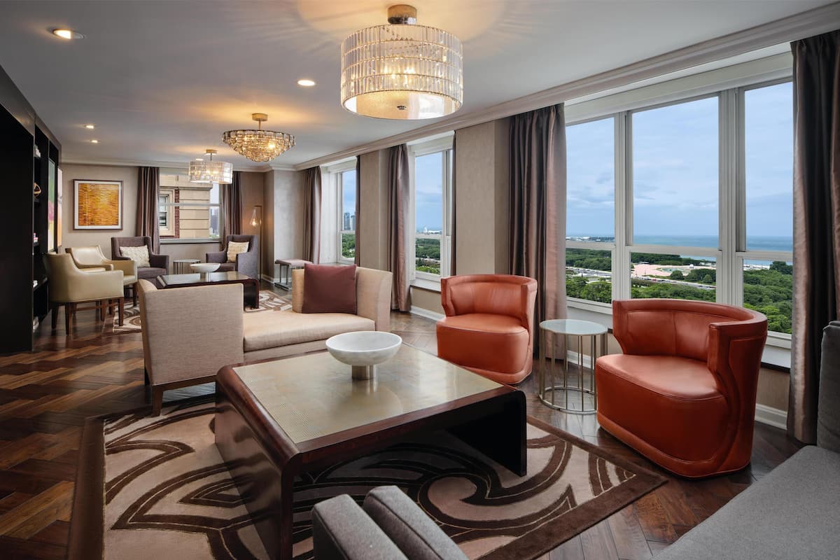 Amplia sala de estar con un gran ventanal que ofrece vistas a la ciudad, una araña y muebles modernos.
