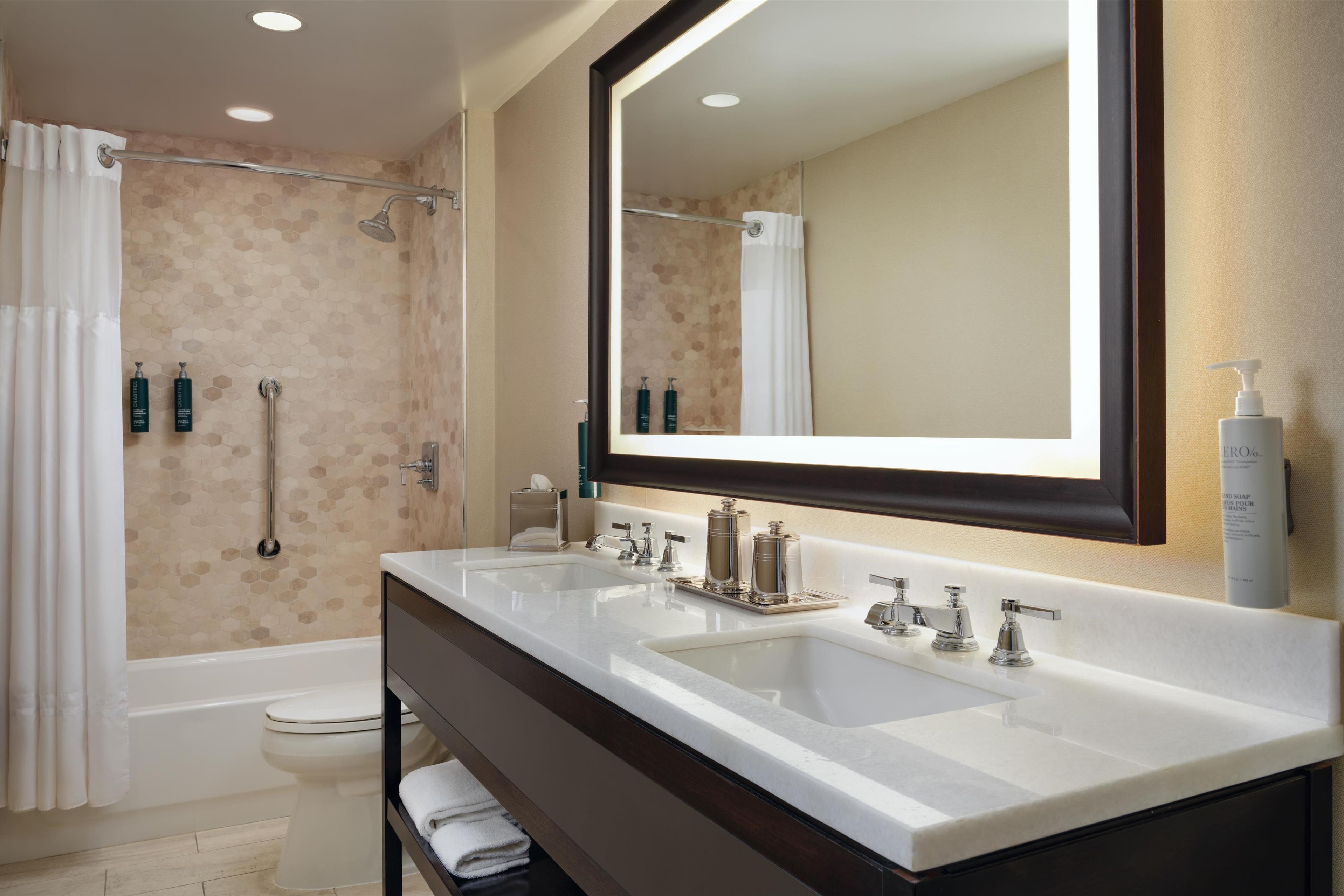 A bathroom with two sinks, a large mirror, and a shower area.