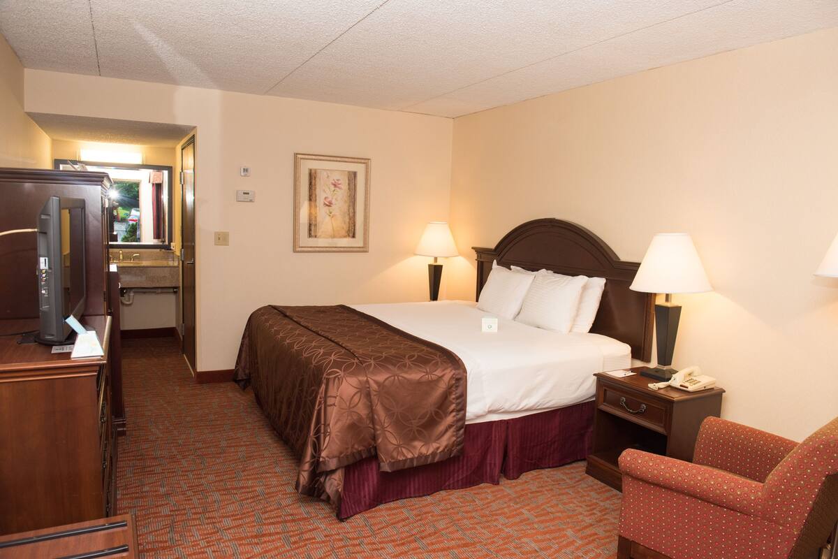 Habitación de hotel con cama, lámparas de noche, un escritorio con computadora y una silla.