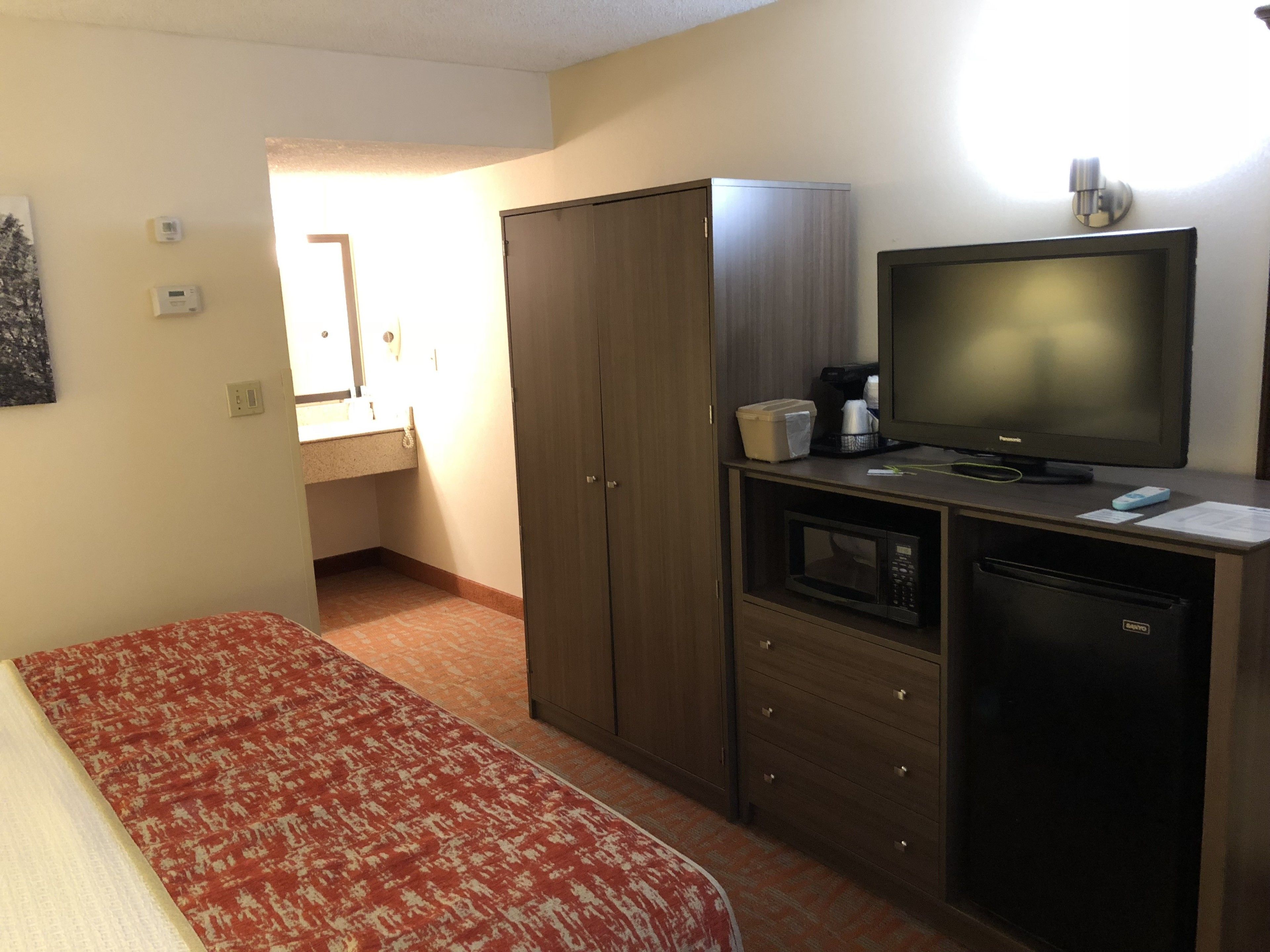 A compact room with a bed, a kitchenette, a TV, and a wardrobe.
