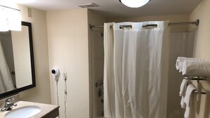 Een badkamer met een wastafel, spiegel, douchegordijn en een handdoekhouder.