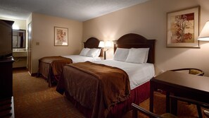 A hotel room with two beds, a desk, a chair, a TV, and a bathroom.