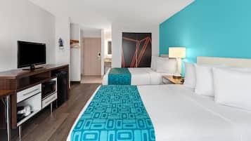 A hotel room with a bed, a desk with a television, a microwave, and a small kitchenette.