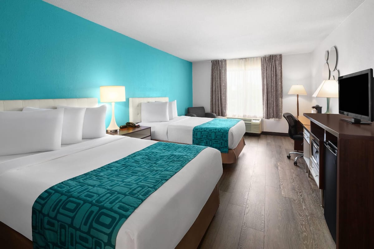 A hotel room with two beds, a desk, a TV, and a wardrobe.
