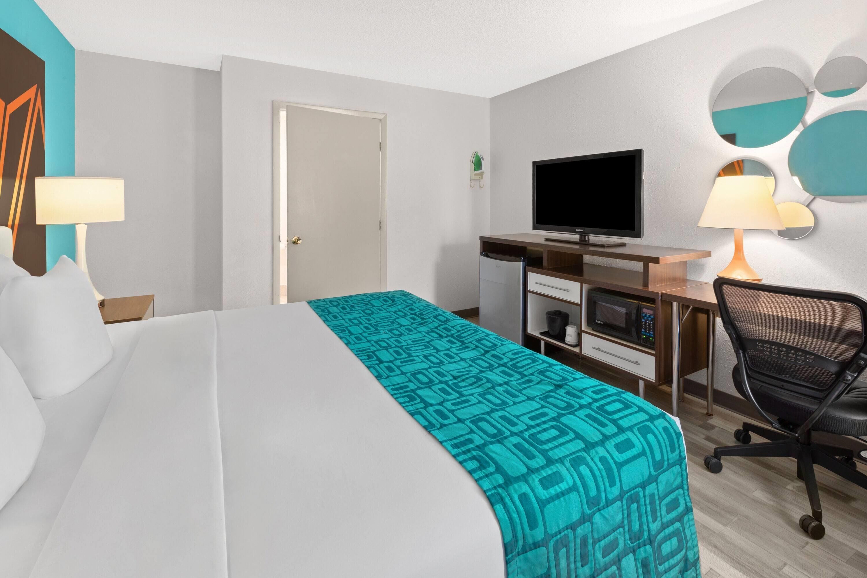 Una camera d'albergo con un letto, una scrivania, una televisione e una sedia.