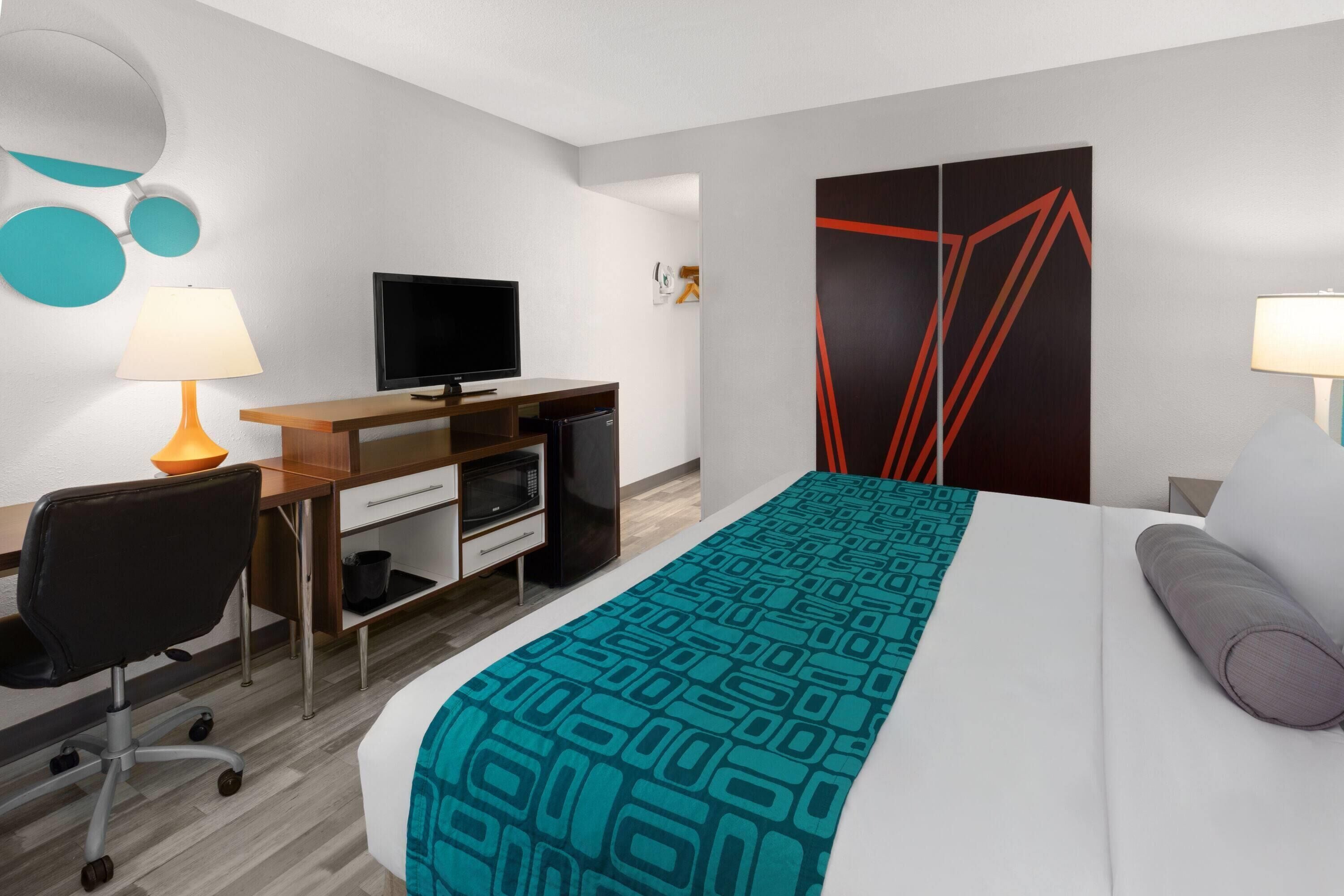 A hotel room with a bed, a desk, a television, and a wardrobe.