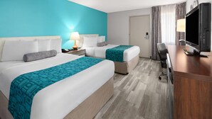 Una habitación de hotel con dos camas, un escritorio, un televisor y una lámpara.