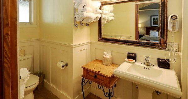 Un baño con inodoro, lavamanos, espejo y toallas.