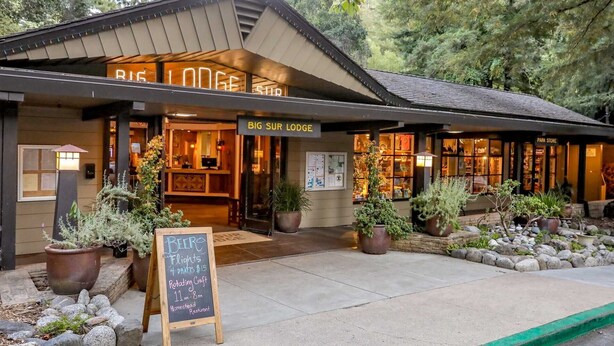 A rustic lodge with a sign reading "BIG SUR LODGE" and a signboard advertising beer flights and rotating craft. - Big Sur Lodge (Big Sur)